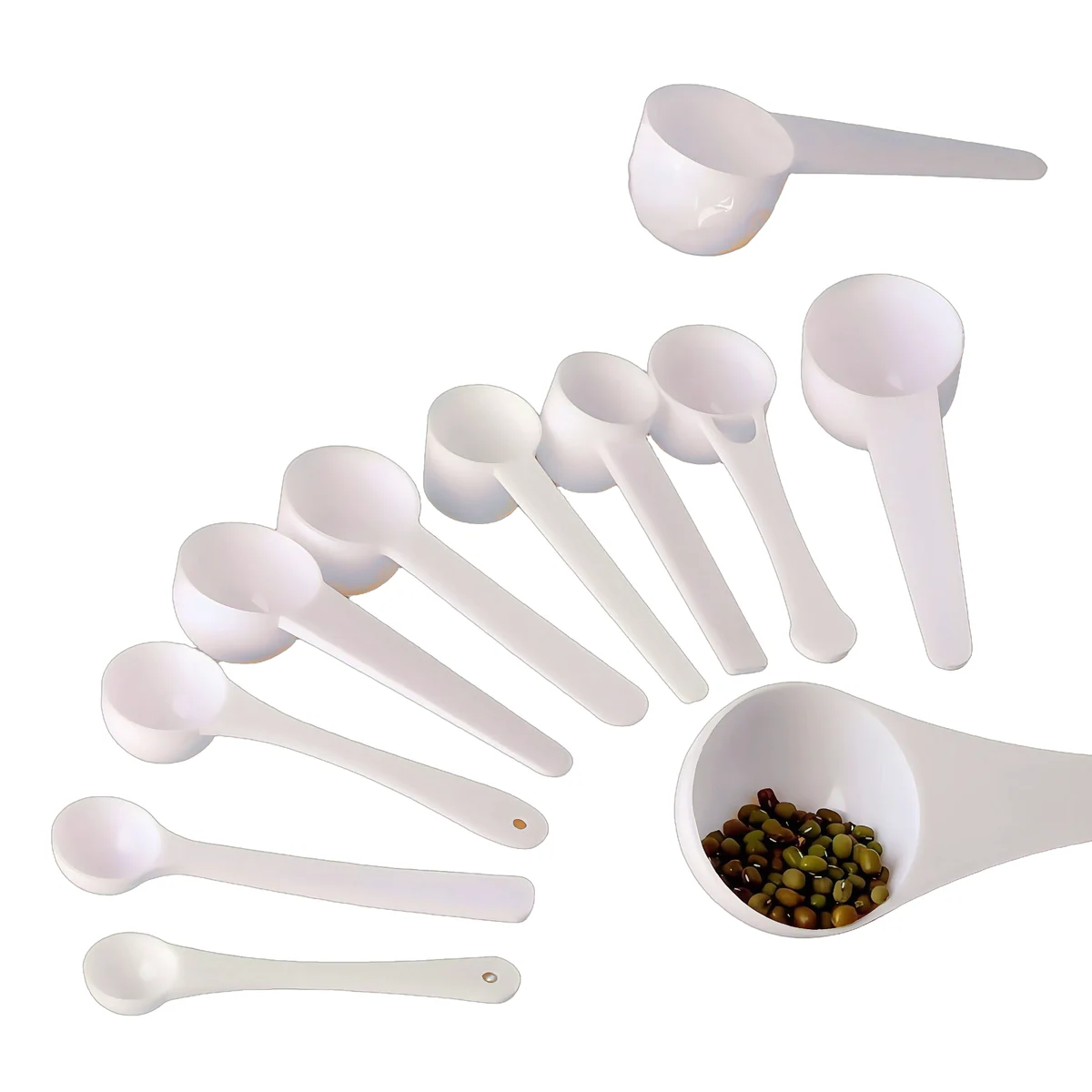 Assortment of white plastic dosing spoons in different marked sizes and bowl shapes